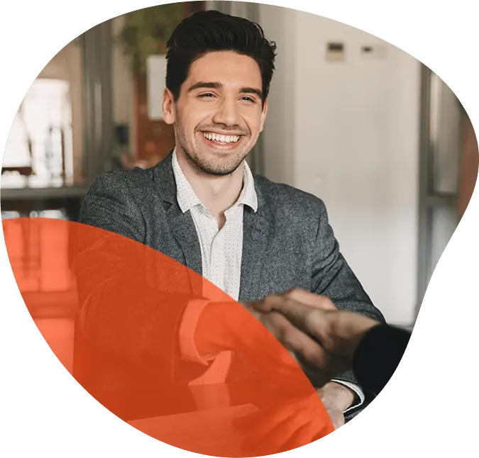 A man smiling while handshaking inside the office.